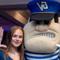 A grad posing for a photo with Louie the Laker.